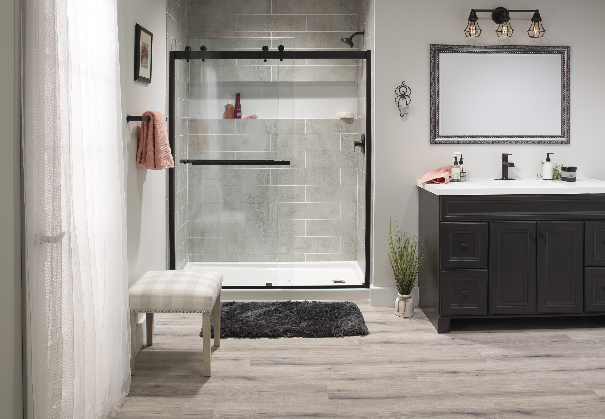 Modern bathroom with a glass-enclosed shower, gray tiled walls, and a dark wood vanity on the right.